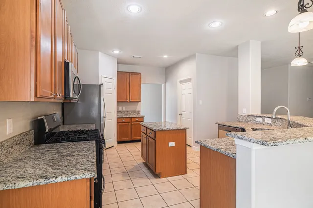 a kitchen with kitchen island granite countertop a sink and cabinets