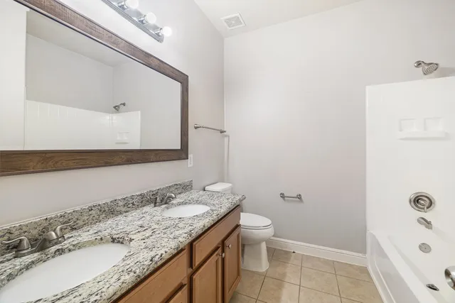 a bathroom with a granite countertop sink a toilet and a mirror