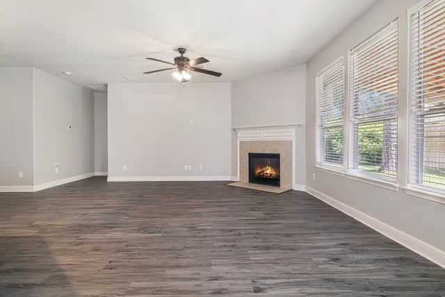 a view of empty room with wooden floor fireplace and fan