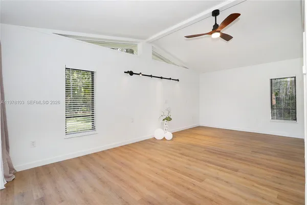 a view of empty room with wooden floor and fan