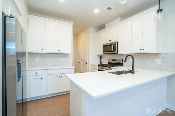 a kitchen with granite countertop white cabinets and stainless steel appliances
