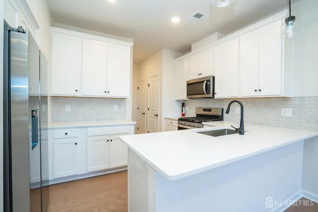 a kitchen with granite countertop white cabinets and stainless steel appliances