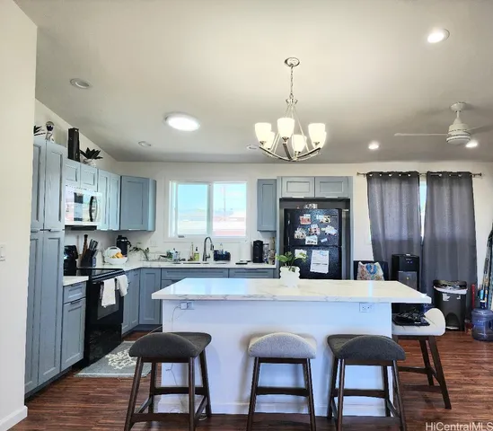 a kitchen with stainless steel appliances granite countertop a stove top oven a sink dishwasher a dining table and chairs with wooden floor