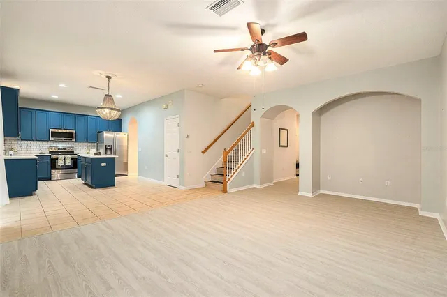 a view of a livingroom with a ceiling fan a kitchen view and a stove top oven