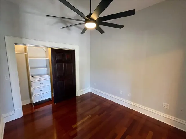 an empty room with chandelier fan and windows