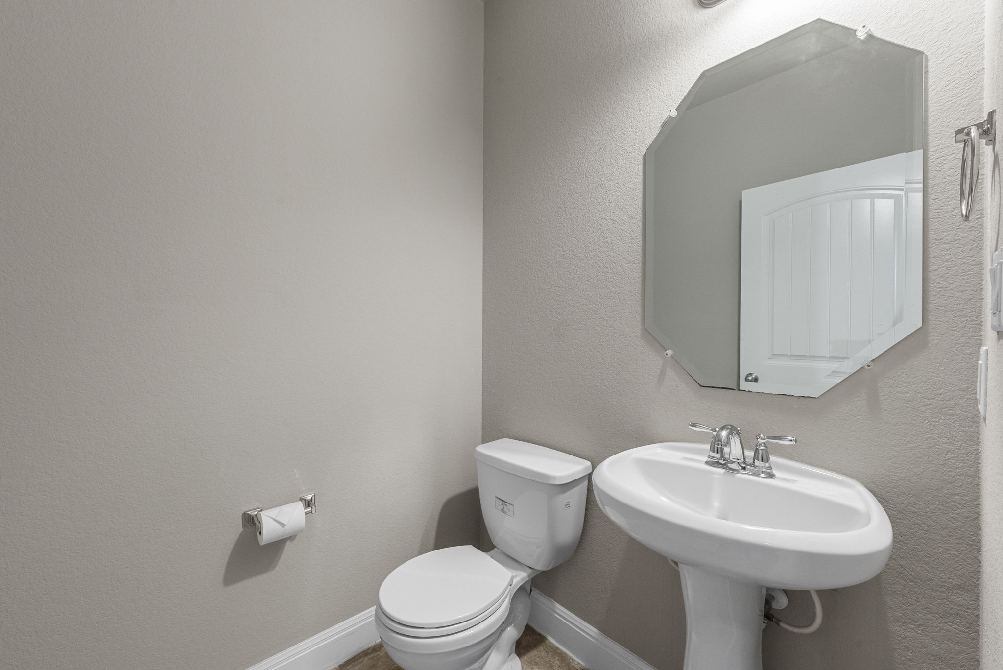 4401 Trinity Woods Street Leander, TX 78641 - Photo 16 of 37 A compact and functional powder room with a sleek pedestal sink and an octagonal mirror.