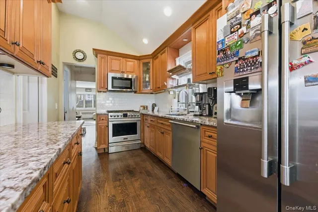 a kitchen with stainless steel appliances granite countertop a refrigerator a stove and a sink with wooden floor