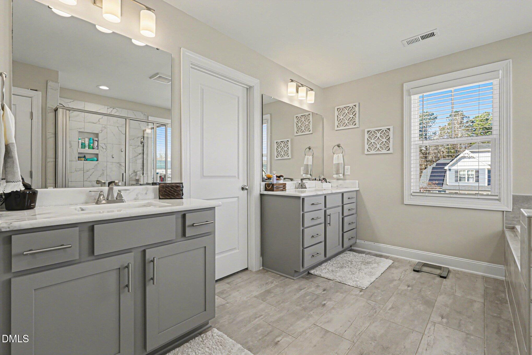 274 Colson Ridge Drive Clayton, NC 27520 - Photo 30 of 48 a spacious bathroom with a double vanity sink a mirror a window and a bathtub