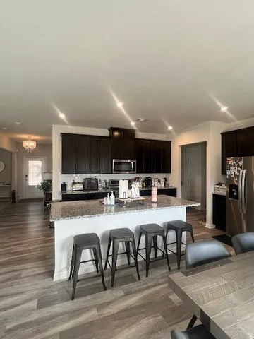 a kitchen with stainless steel appliances a dining table chairs and a wooden floor