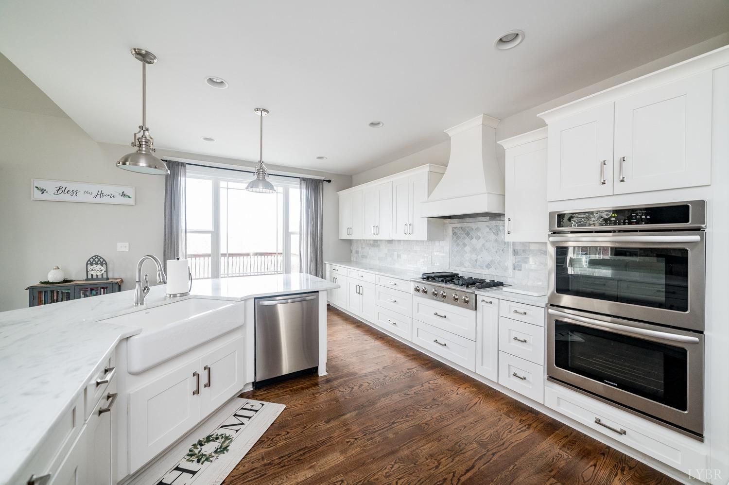 967 Lynbrook Road Rustburg, VA 24588 - Photo 46 of 99 a large white kitchen with stainless steel appliances granite countertop a stove a sink dishwasher a microwave oven with cabinets and wooden floor