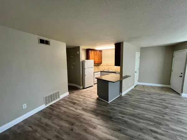 a view of kitchen with granite countertop cabinets and refrigerator