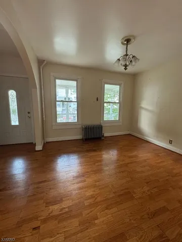 a view of an empty room with window and wooden floor