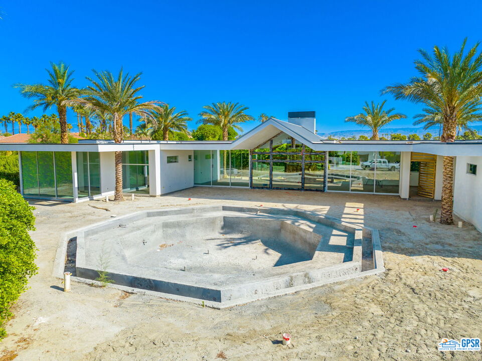 1 Makena Lane Rancho Mirage, CA 92270 - Photo 7 of 22 a view of a white house with a swimming pool lawn chairs and a yard