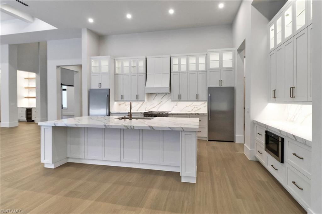 5174 Sycamore Drive Naples, FL 34119 - Photo 13 of 39 a kitchen with stainless steel appliances granite countertop a stove a sink and a refrigerator