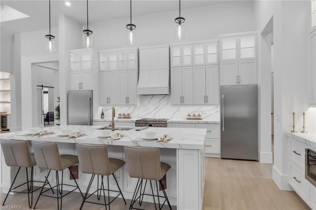 5174 Sycamore Drive Naples, FL 34119 - Photo 19 of 50 a kitchen with stainless steel appliances kitchen island granite countertop a dining table chairs and white cabinets