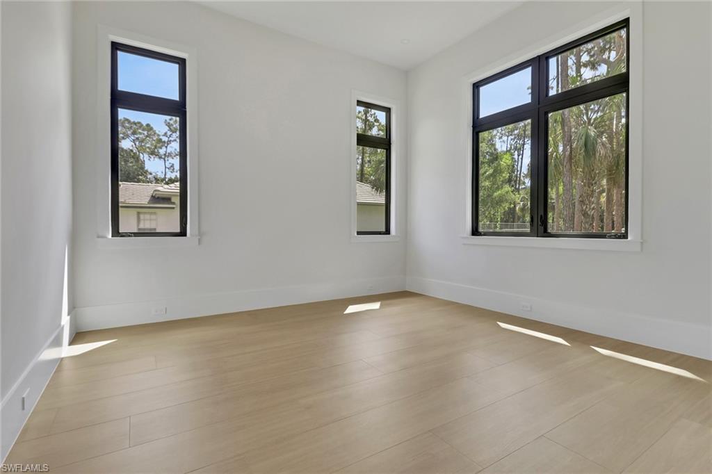 5174 Sycamore Drive Naples, FL 34119 - Photo 22 of 39 an empty room with wooden floor and windows