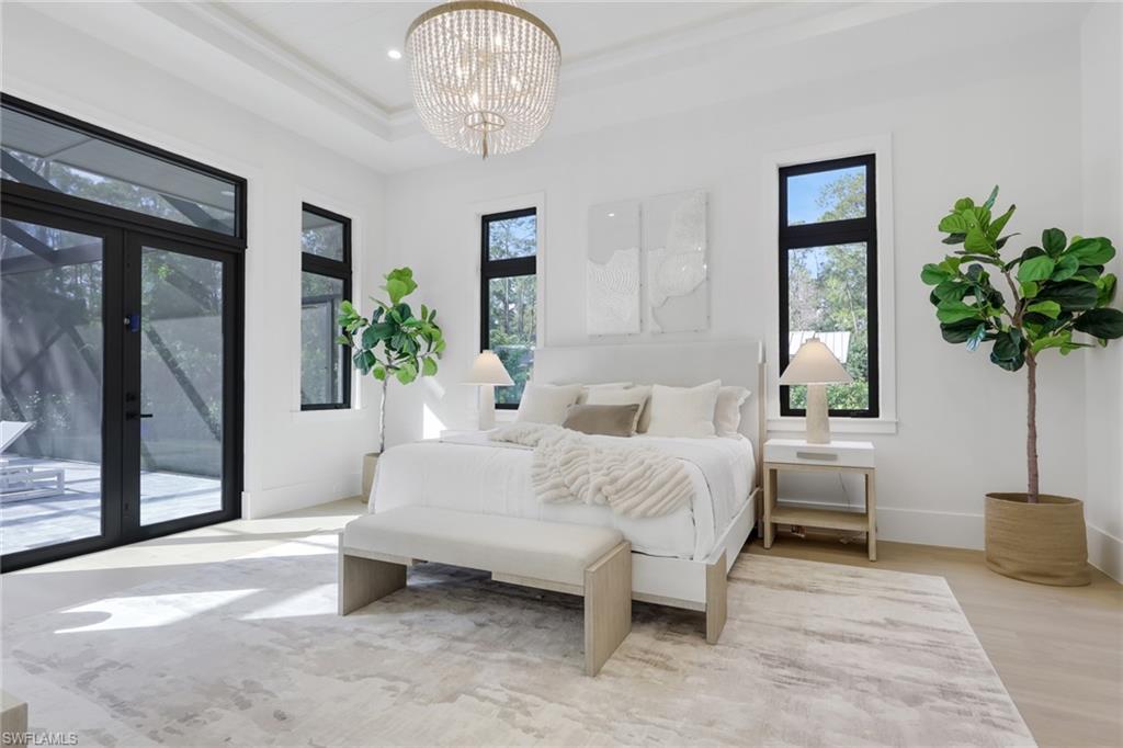 5174 Sycamore Drive Naples, FL 34119 - Photo 24 of 50 a bedroom with a bed and a chandelier