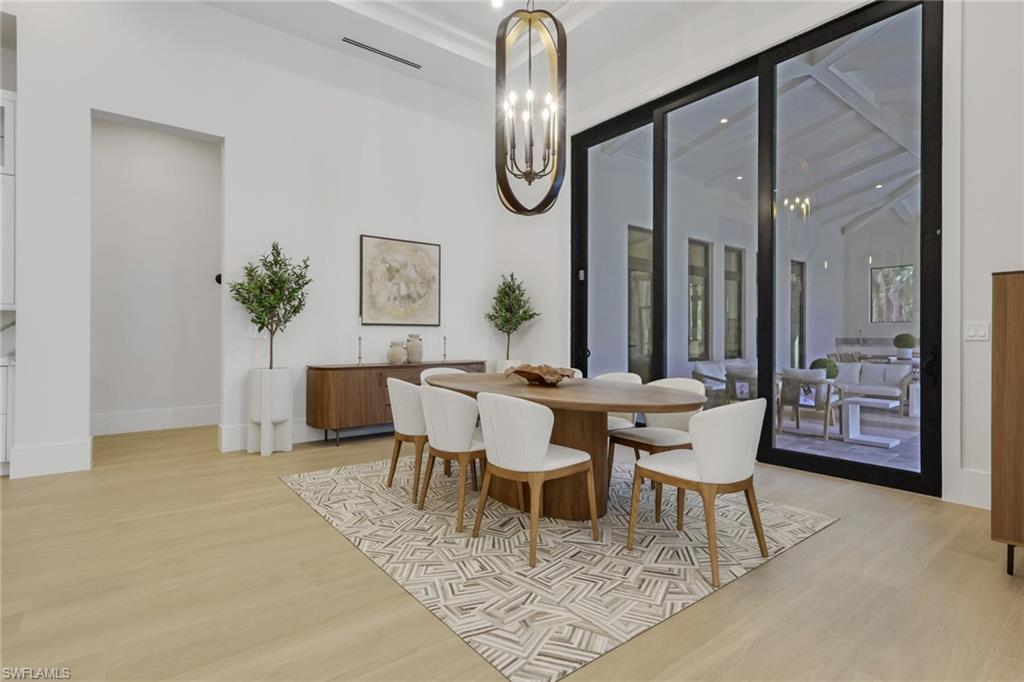 5174 Sycamore Drive Naples, FL 34119 - Photo 9 of 50 a dining room with furniture a potted plant and a rug