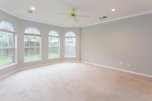 an empty room with windows and ceiling fan
