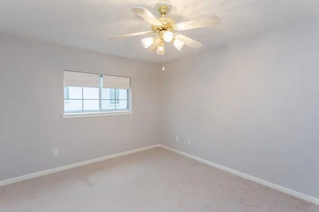 an empty room with windows and chandelier fan