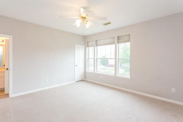 an empty room with windows and chandelier fan