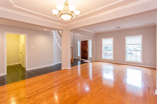 a view of an empty room with window and wooden floor