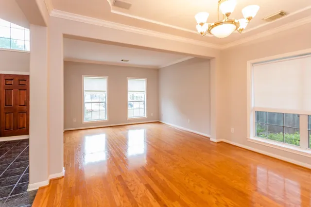 a view of an empty room with a window and wooden floor