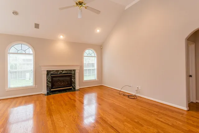 an empty room with windows fireplace and wooden floor