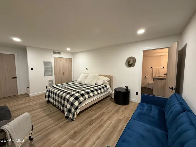 a spacious bedroom with a bed and wooden floor