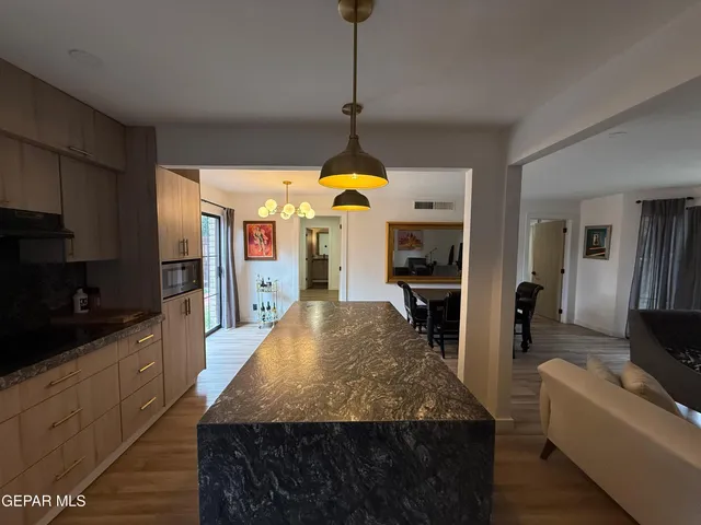 a large kitchen with kitchen island a counter top space a sink stainless steel appliances and cabinets