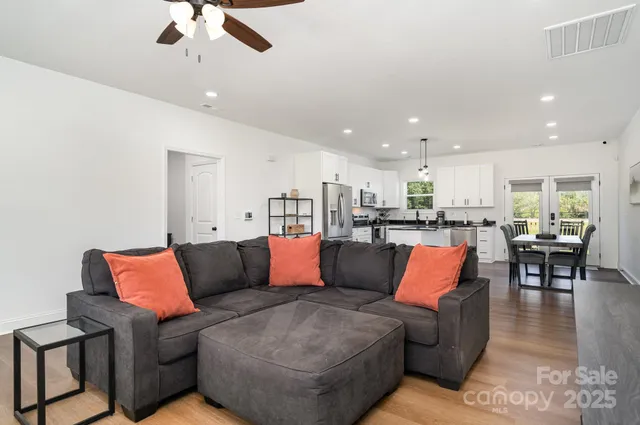 a living room with furniture kitchen view and a chandelier