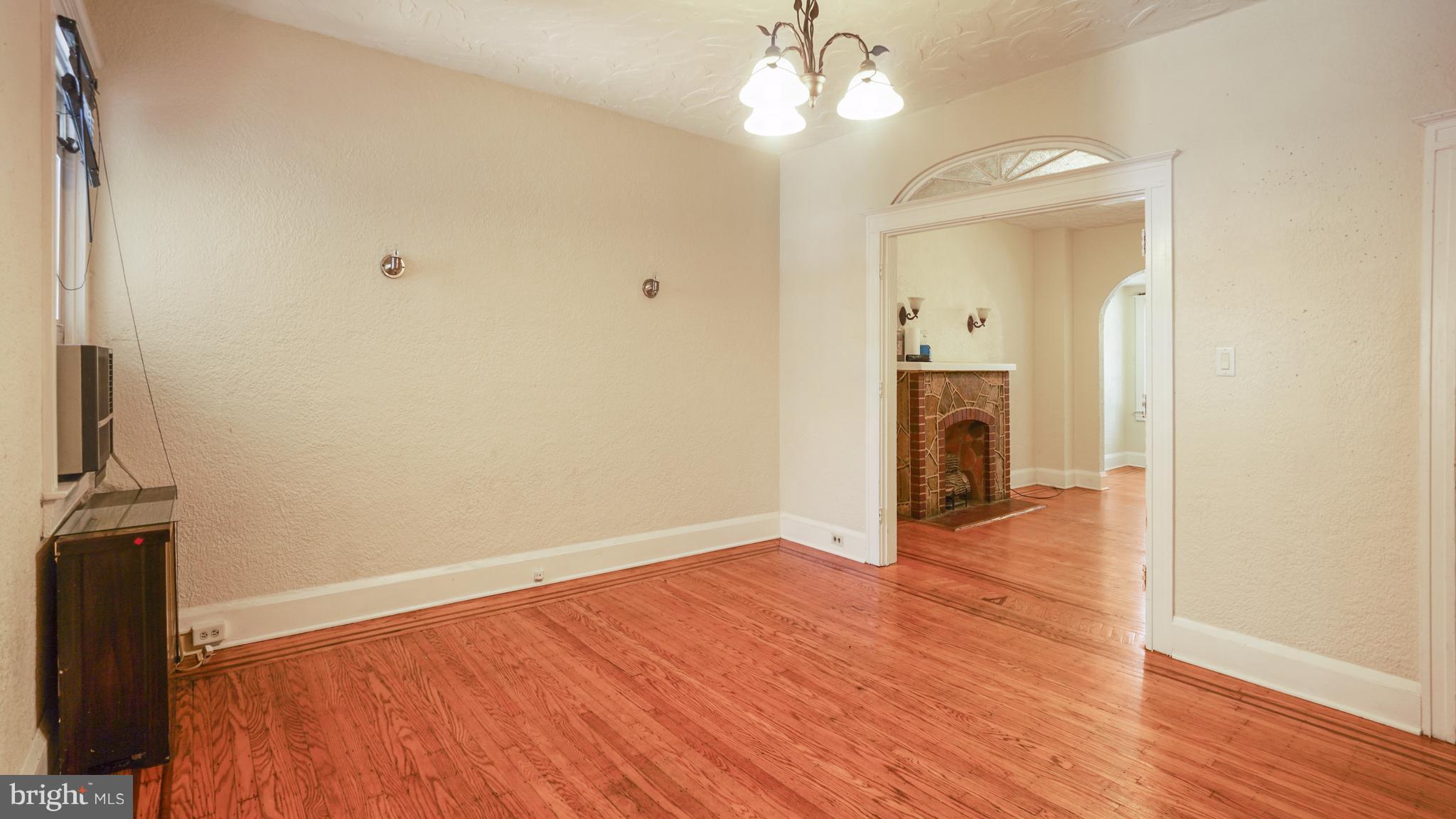 6214 Frederick Road Catonsville, MD 21228 - Photo 3 of 10 wooden floor in an empty room with a fireplace