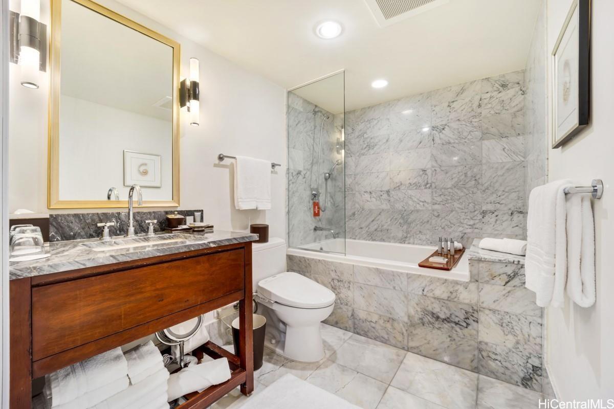 223 Saratoga Road, Unit 2006 Honolulu, HI 96815 - Photo 8 of 15 a bathroom with a granite countertop sink a toilet a mirror and shower