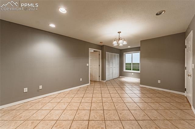 1027 County Road LL Fowler, CO 81039 - Photo 17 of 37 Unfurnished room featuring an inviting chandelier and light tile patterned floors