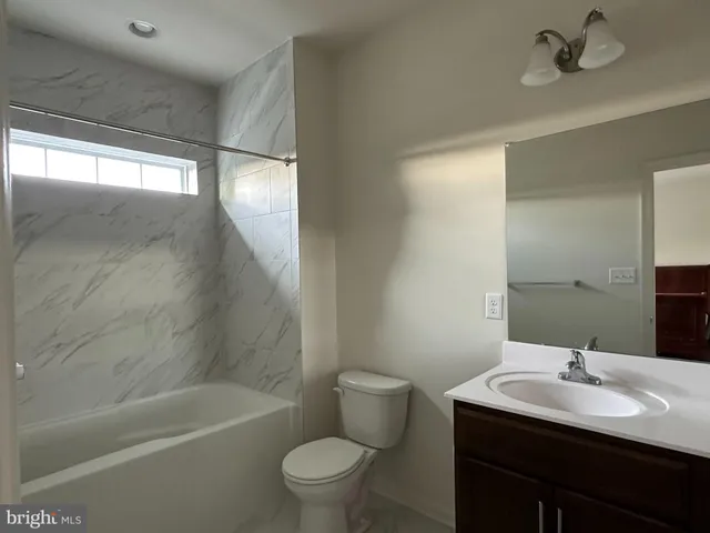 a bathroom with a bathtub shower sink vanity mirror and toilet