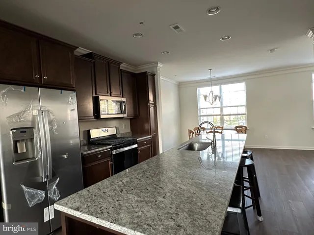 a kitchen with stainless steel appliances granite countertop a sink a stove and refrigerator