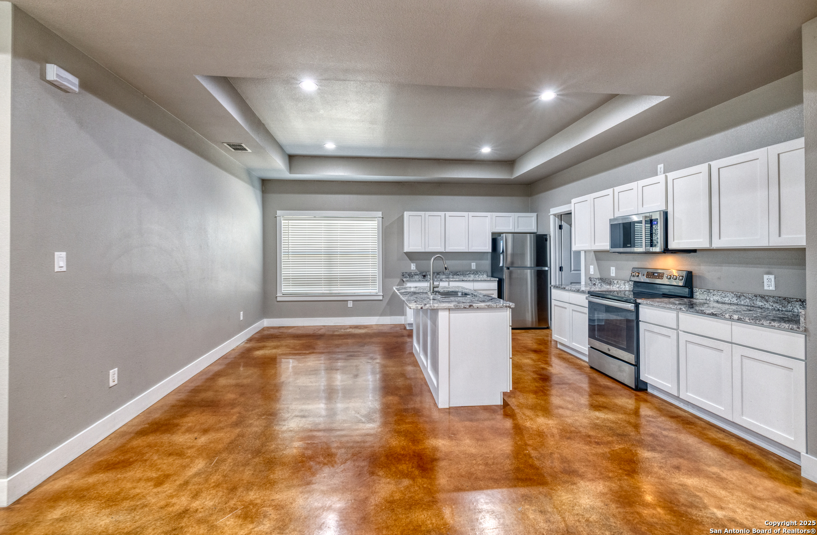 413 Guajillo Uvalde, TX 78801 - Photo 5 of 23 a large kitchen with kitchen island a stove a sink dishwasher a refrigerator and white cabinets with wooden floor