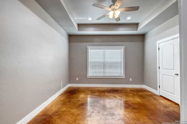 an empty room with a chandelier fan and windows