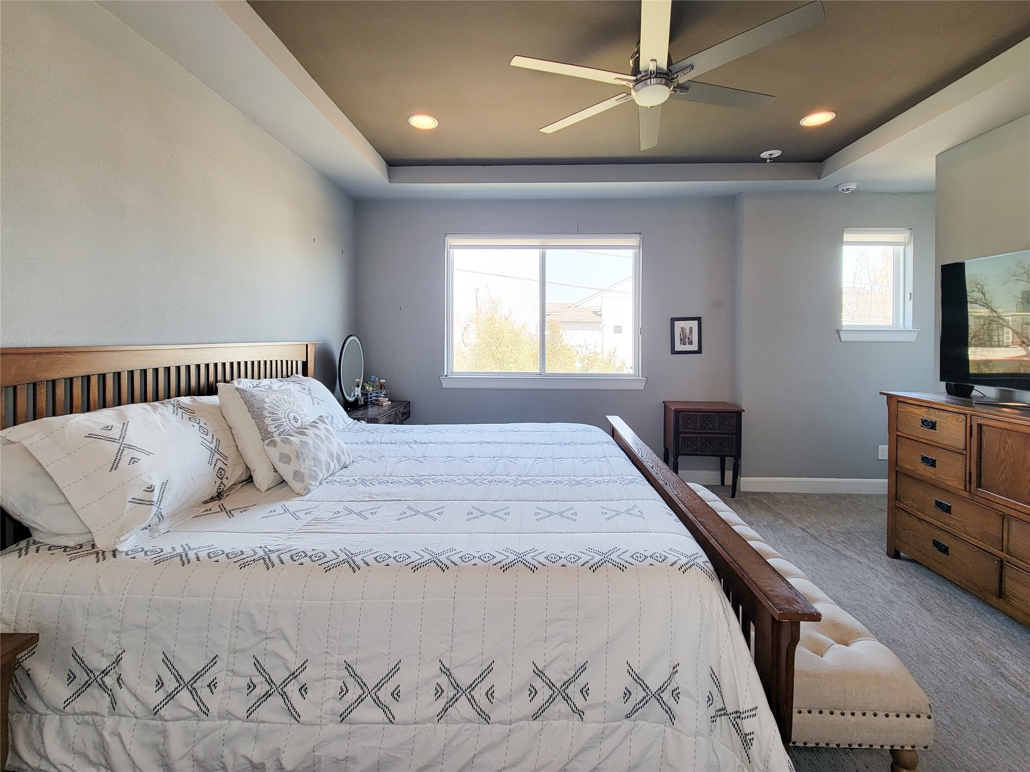 1705 Eado Point Lane Houston, TX 77003 - Photo 41 of 50 Spacious Primary bedroom with a cozy ambiance, featuring an elegant ceiling fan, ample natural light from a generous window, two walk-in closets, and an accent recessed ceiling.