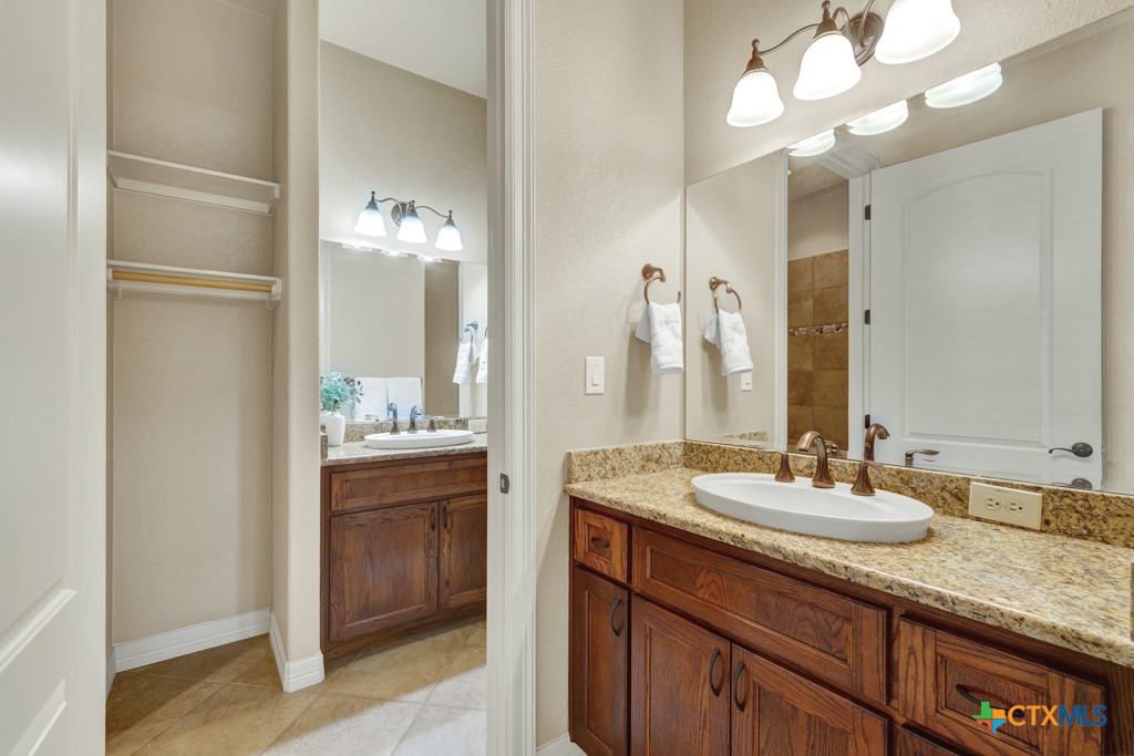7607 Sky Loop Garden Ridge, TX 78266 - Photo 26 of 43 a bathroom with a granite countertop sink a large mirror and a shower