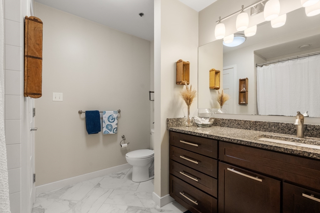 156-168 Terrace Street, Unit 402 Boston, MA 02120 - Photo 12 of 31 a bathroom with a granite countertop toilet sink and mirror