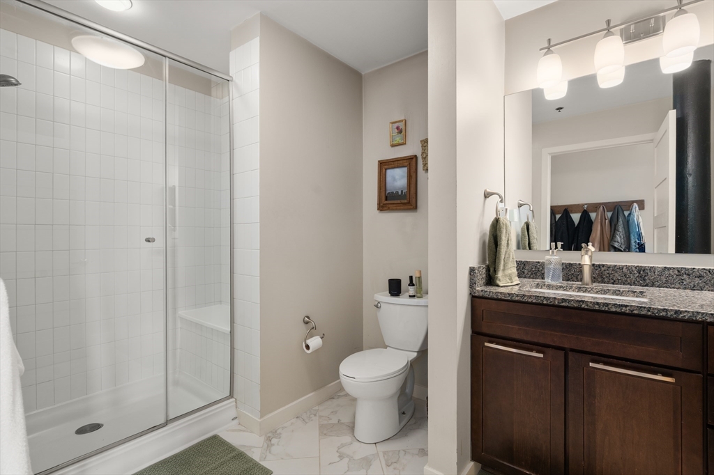 156-168 Terrace Street, Unit 402 Boston, MA 02120 - Photo 20 of 31 a bathroom with a granite countertop sink toilet a mirror and shower