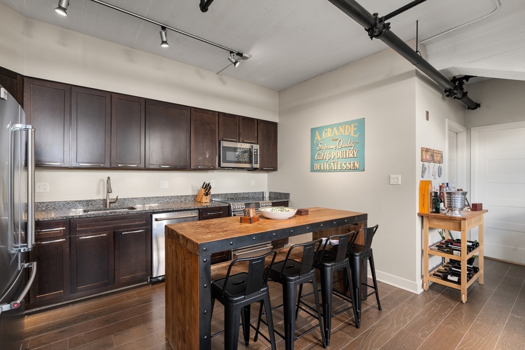 156-168 Terrace Street, Unit 402 Boston, MA 02120 - Photo 5 of 31 a kitchen with stainless steel appliances granite countertop a sink a stove a table and chairs