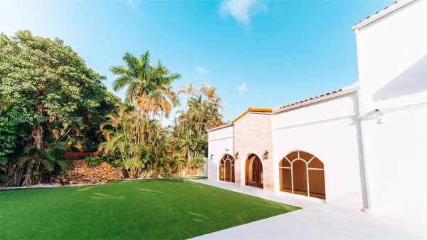 a view of a white house with a big yard and large trees