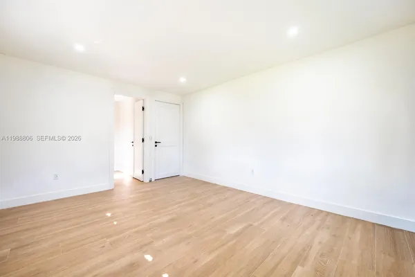 an empty room with wooden floor ceiling fan and windows