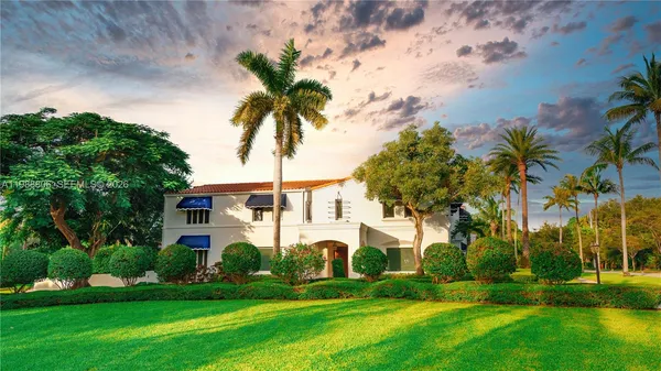 a front view of a house with a garden and trees