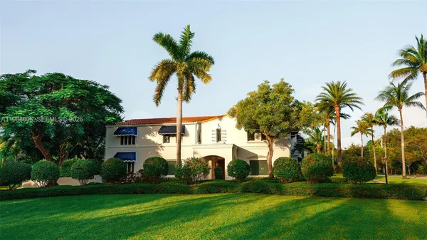 a front view of a house with a garden and trees