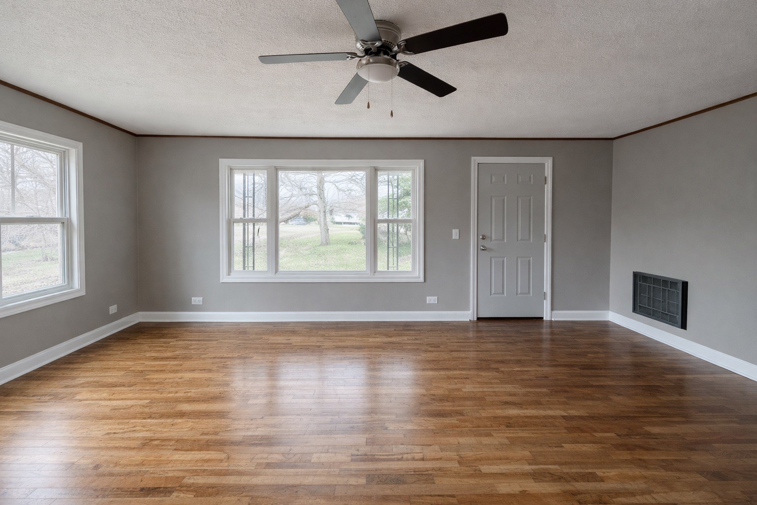 109 Apple Tree Street Arlington, KY 42021 - Photo 12 of 18 an empty room with wooden floor chandelier fan and windows
