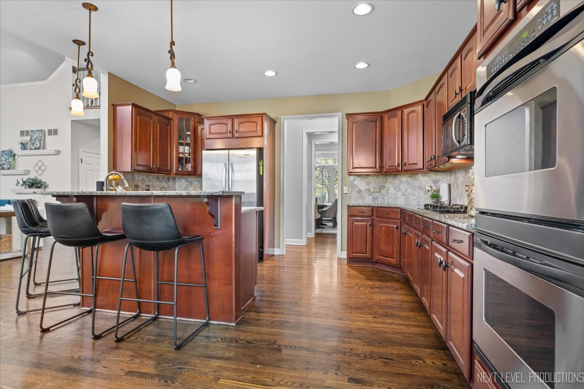 2236 Red Maple Lane Aurora, IL 60502 - Photo 17 of 50 a kitchen with stainless steel appliances granite countertop a stove top oven a refrigerator a sink and chairs