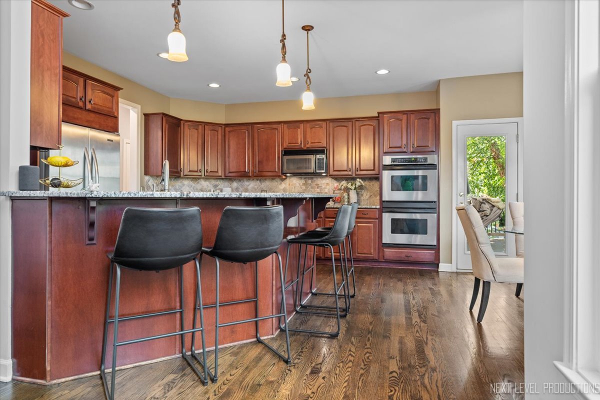 2236 Red Maple Lane Aurora, IL 60502 - Photo 8 of 50 a kitchen with stainless steel appliances kitchen island granite countertop a table chairs in it and wooden floors